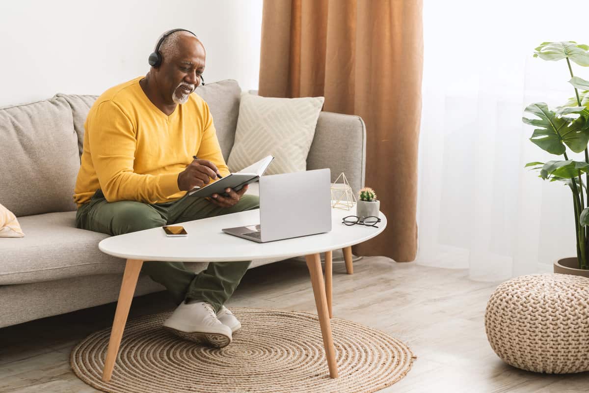 A man on a couch working on a laptop computer to access Benefits.gov.